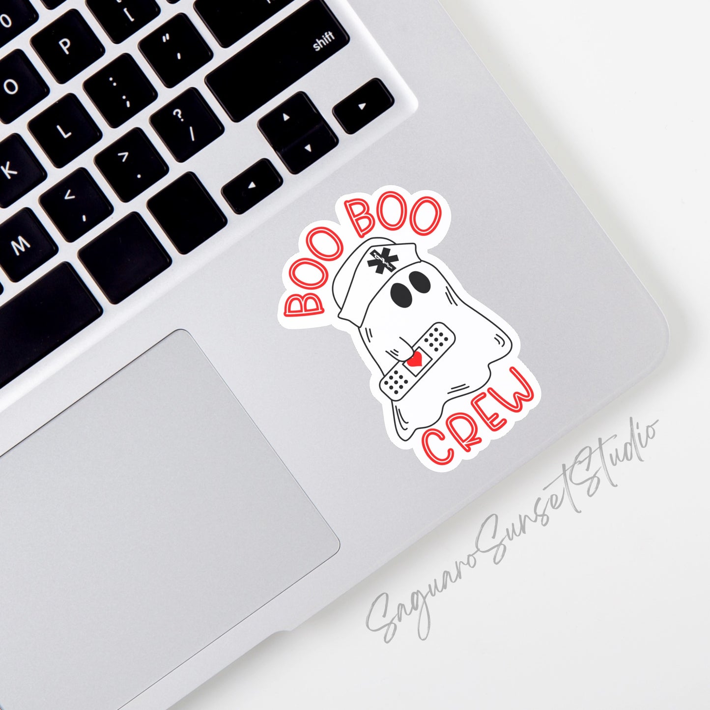 Sticker of a ghost with a bandage, wearing a nurse hat, and "boo boo crew" text in red. The sticker is placed on the corner of a laptop.