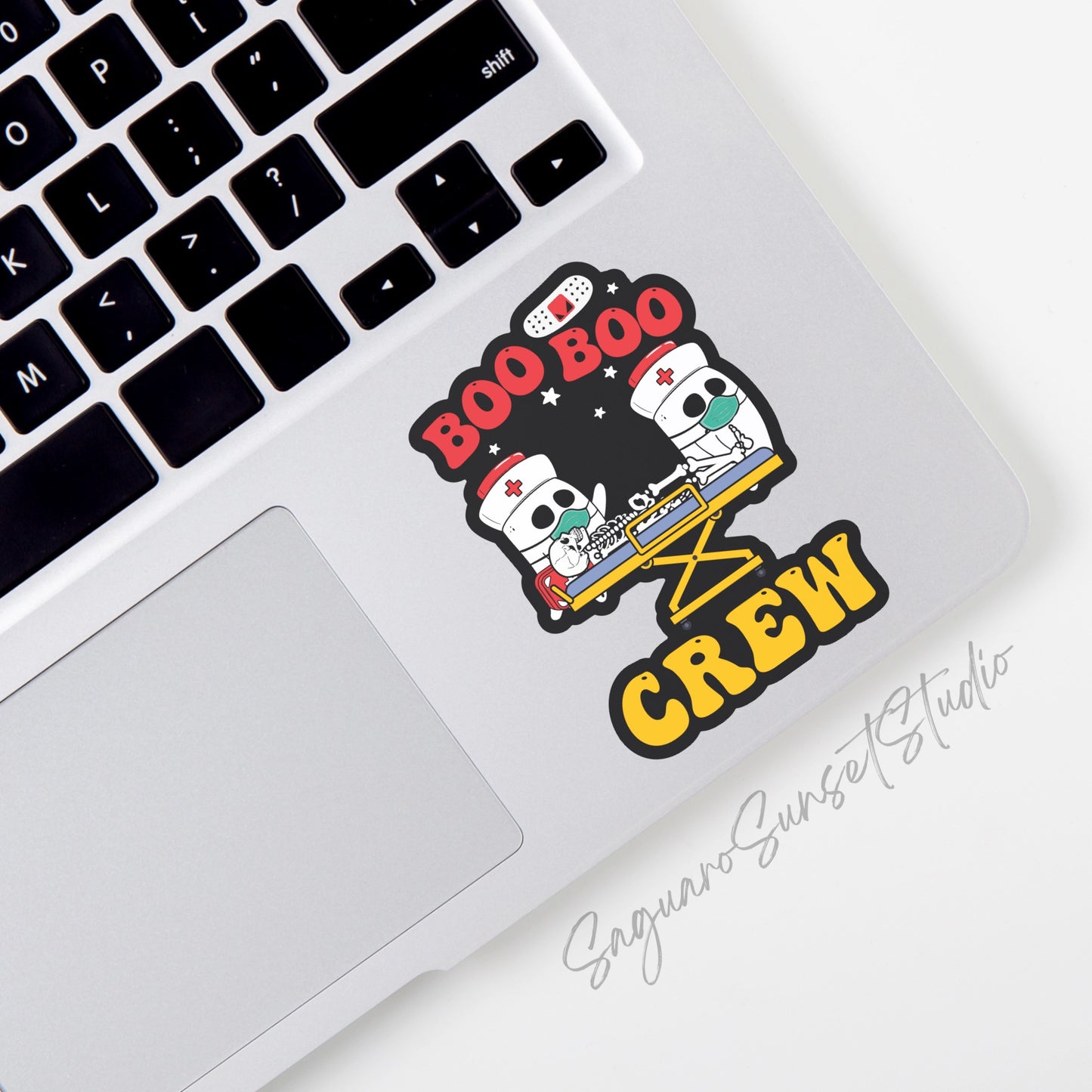 A sticker featuring the phrase "Boo Boo Crew" in bold red and yellow text. The design includes cartoon ghost nurses in masks tending to a skeleton patient on a stretcher, set against a starry black background.