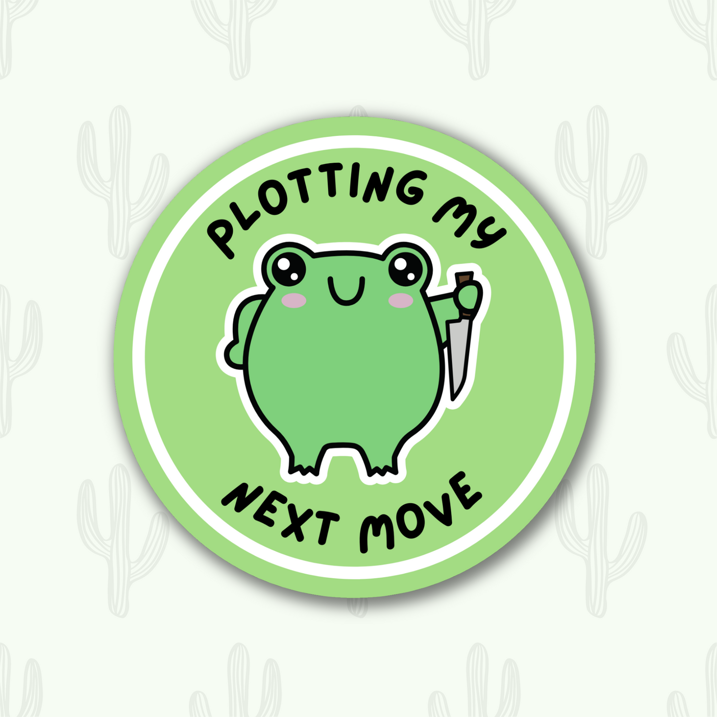 A green circle sticker featuring a mischievous frog holding a knife, with the text 'Plotting my next move' 