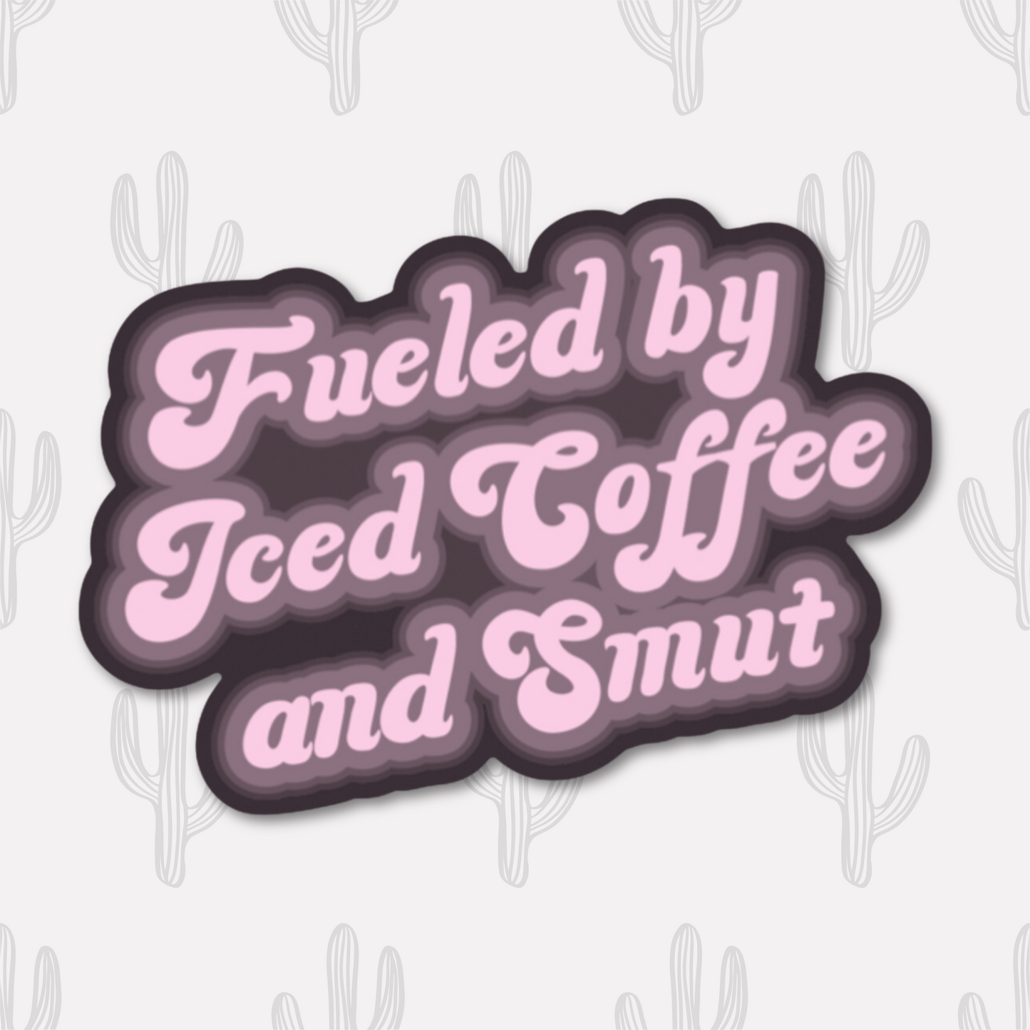 A vinyl sticker with the phrase "Fueled by Iced Coffee and Smut" in playful pink text on a dark background