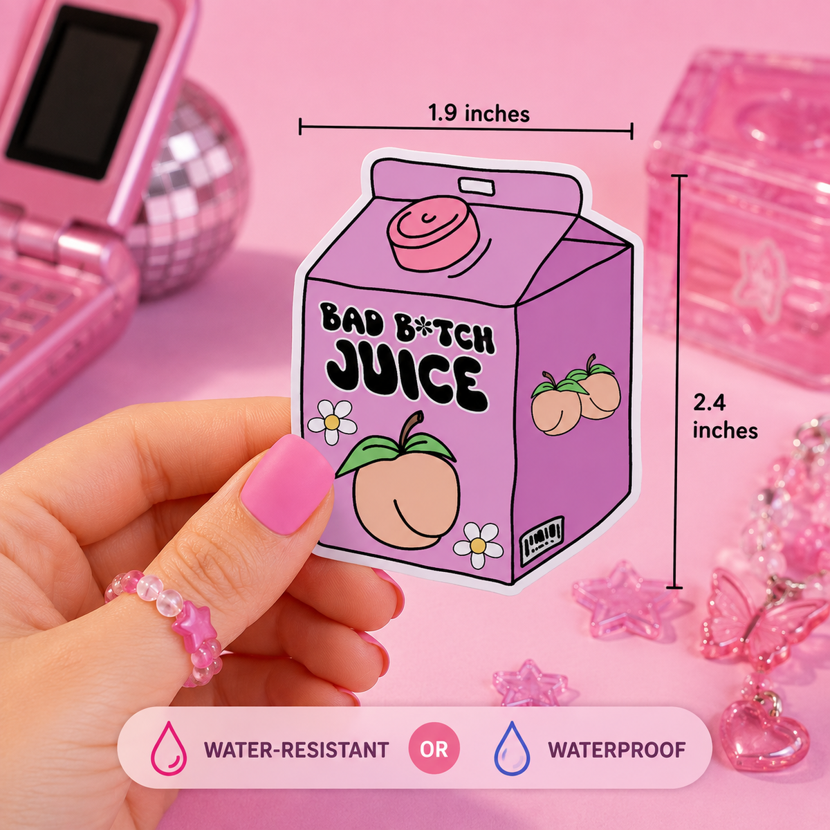 A hand holds a pink juice carton-shaped sticker with the text 'BAD B*TCH JUICE' and peach illustrations. The image includes dimension markers showing 1.9 inches wide by 2.4 inches tall