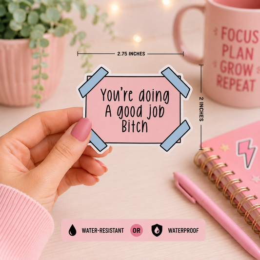 A hand holds a die-cut sticker with the text 'You're doing A good job Bitch' in black lettering on a pink background, surrounded by light blue tape graphics. The image includes dimension lines showing the sticker is 2.75 inches wide by 2 inches tall