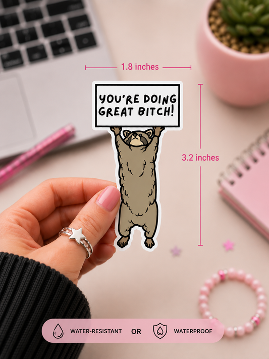 A hand holds a die-cut sticker featuring a cartoon raccoon holding a sign that reads 'YOU'RE DOING GREAT BITCH!' with dimension lines showing 1.8 inches wide by 3.2 inches tall