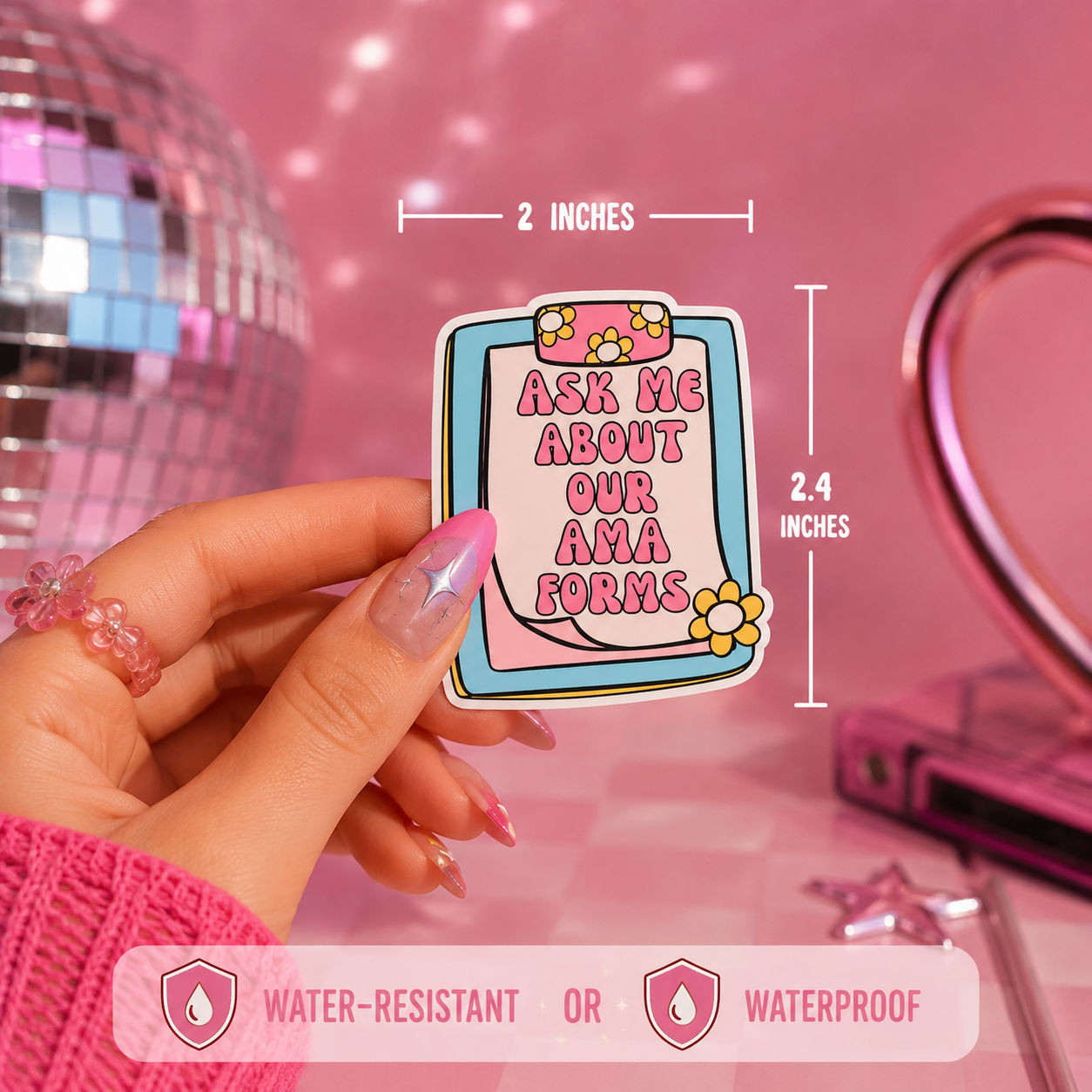 A hand holds a die-cut sticker with a clipboard graphic and the text 'ASK ME ABOUT OUR AMA FORMS' in pink lettering. White dimension lines show the pin is 2 inches wide by 2.4 inches tall.