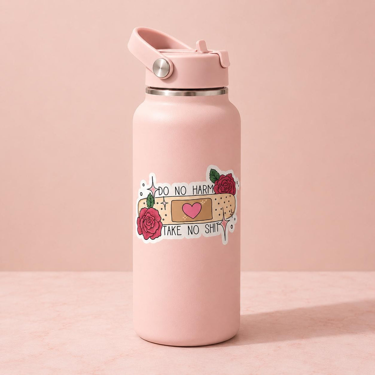 A light pink insulated water bottle with a matching lid, featuring a graphic sticker of a bandage, roses, and the text 'DO NO HARM TAKE NO SHIT' on a soft pink background.