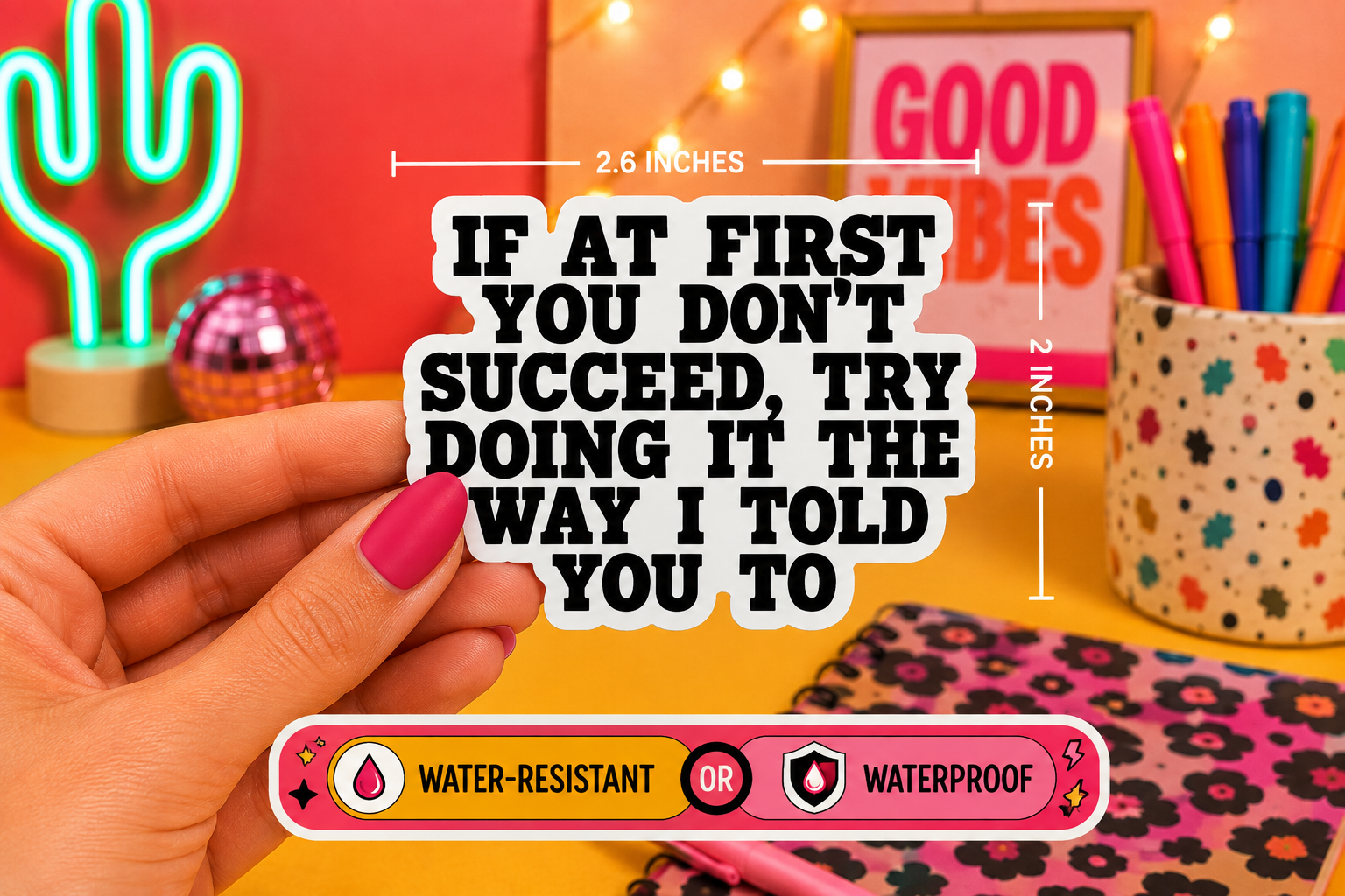 A hand holds a die-cut sticker with the text 'IF AT FIRST YOU DON'T SUCCEED, TRY DOING IT THE WAY I TOLD YOU TO' in bold black letters on a white background. The image includes dimension lines showing the sticker is 2.6 inches wide by 2 inches tall