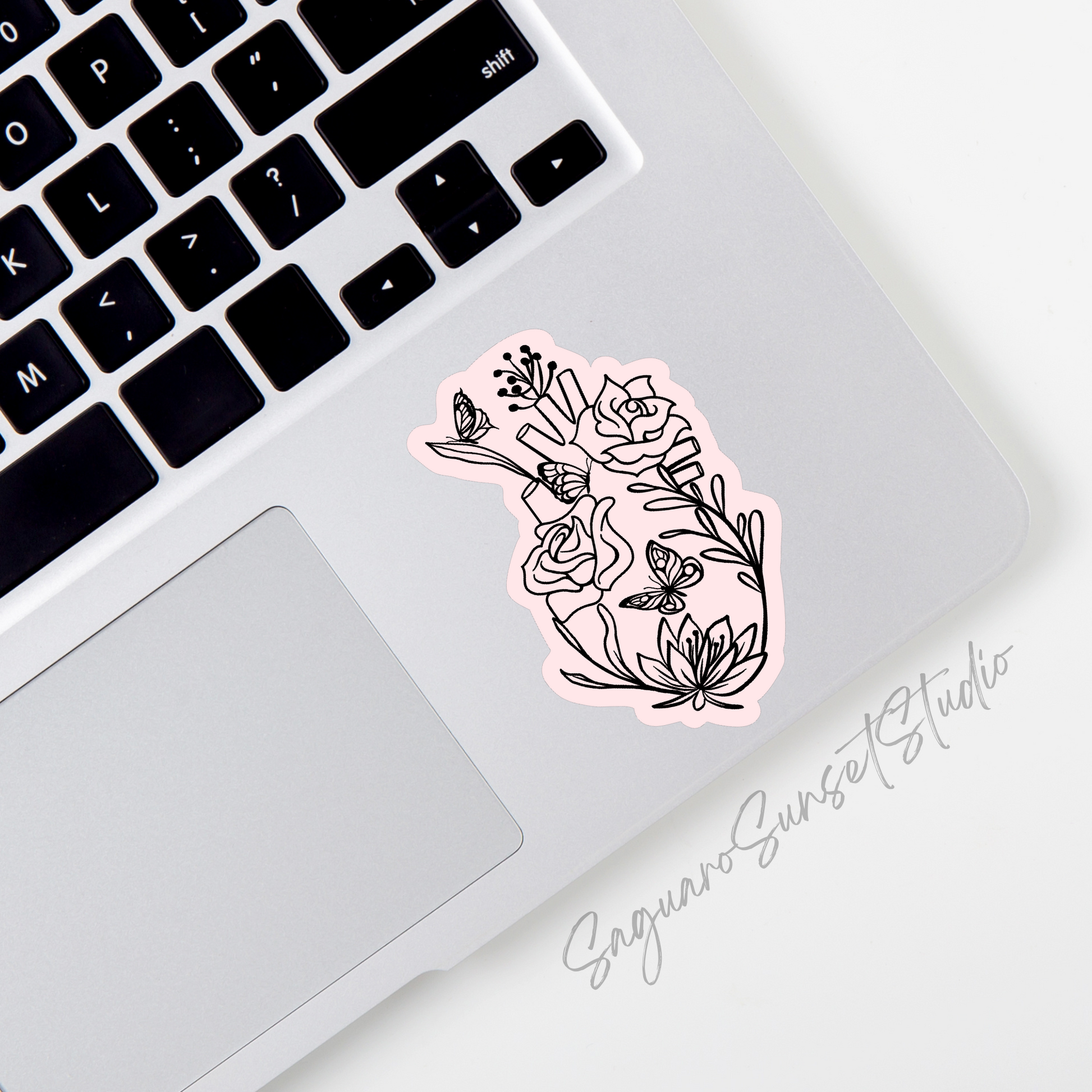 A pink sticker of an anatomical heart adorned with butterflies and flowers on the bottom right corner of a laptop.