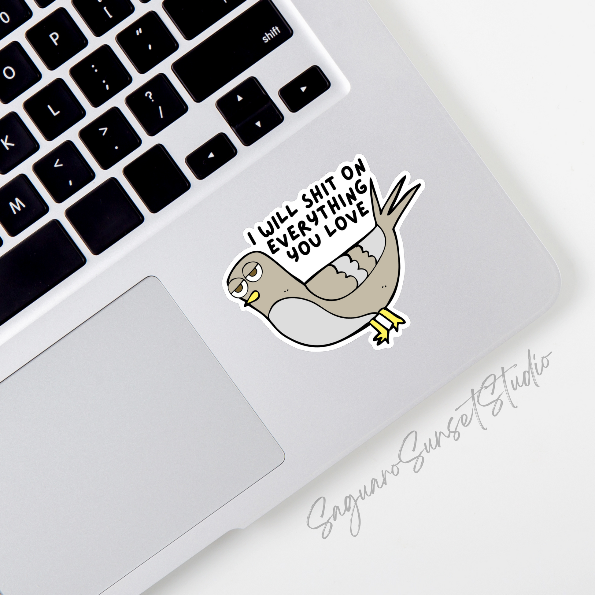 A sticker of a brown and grey pigeon with the phrase 'I will shit on everything you love' on the corner of a laptop.