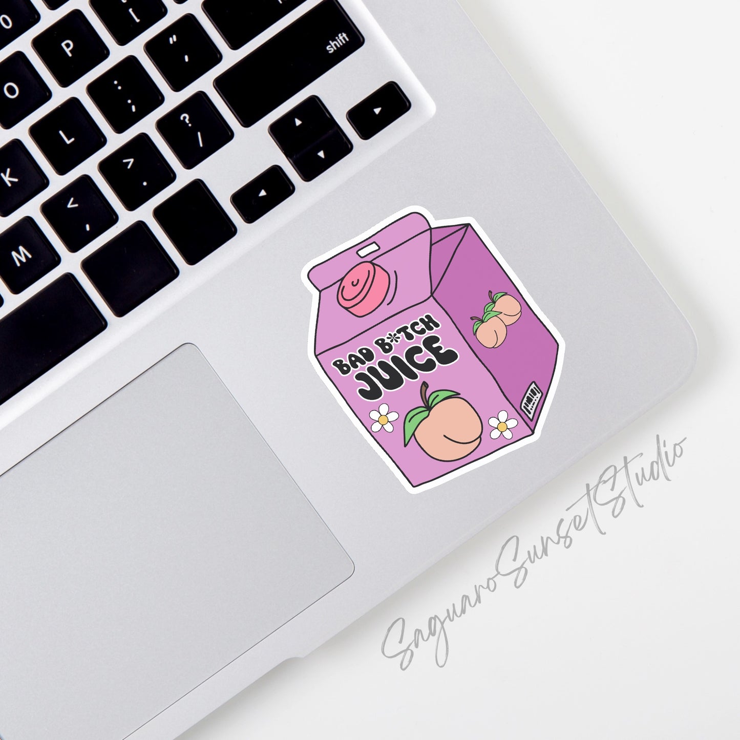 A Colorful sticker on the corner of a laptop showcasing a purple juicebox with a peach and the words 'bad b*tch juice', embellished with daisies.