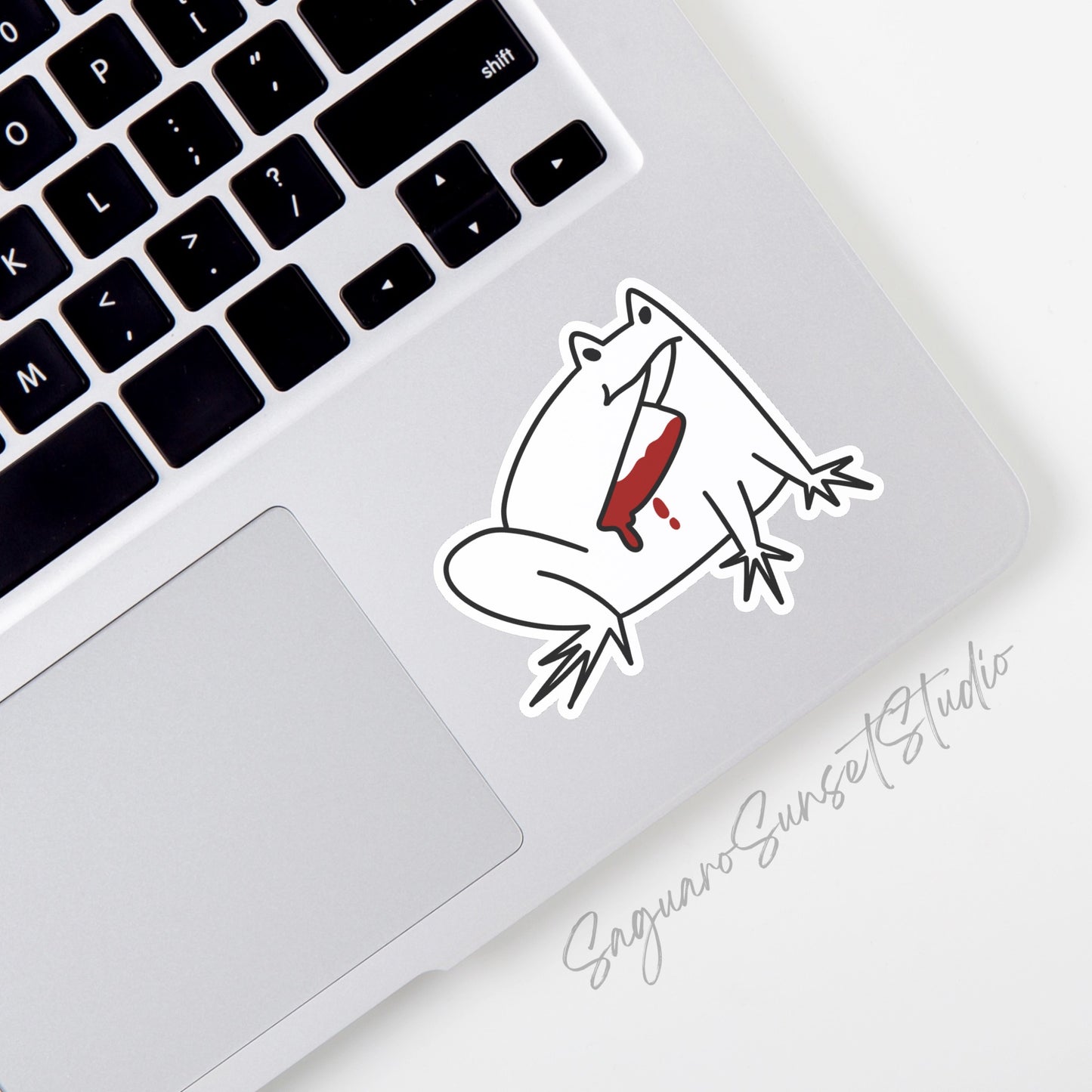 A vinyl sticker featuring a white frog holding a bloodied knife in its mouth