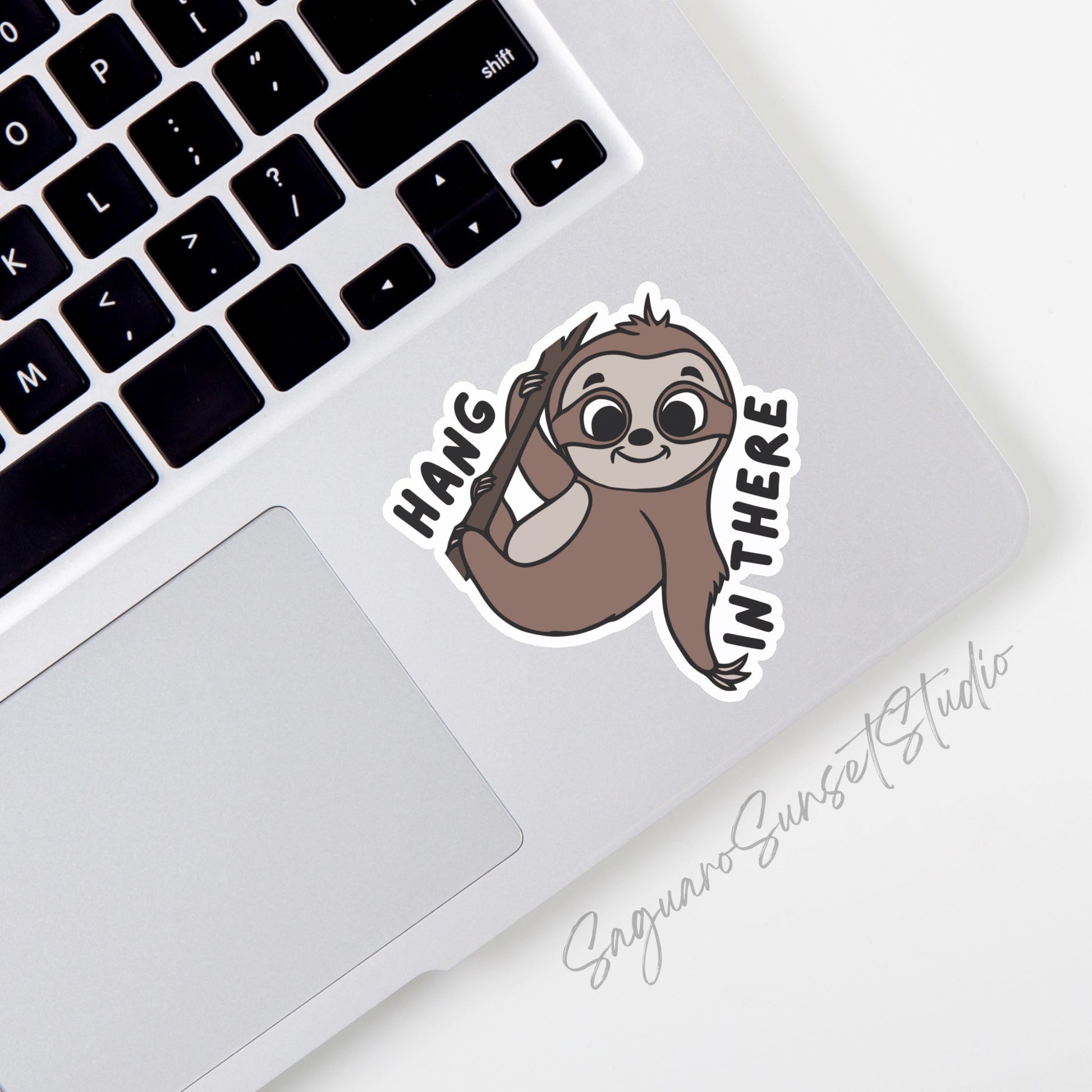 A vinyl sticker featuring a cute sloth hanging from a branch with the phrase "Hang in There!" written around it