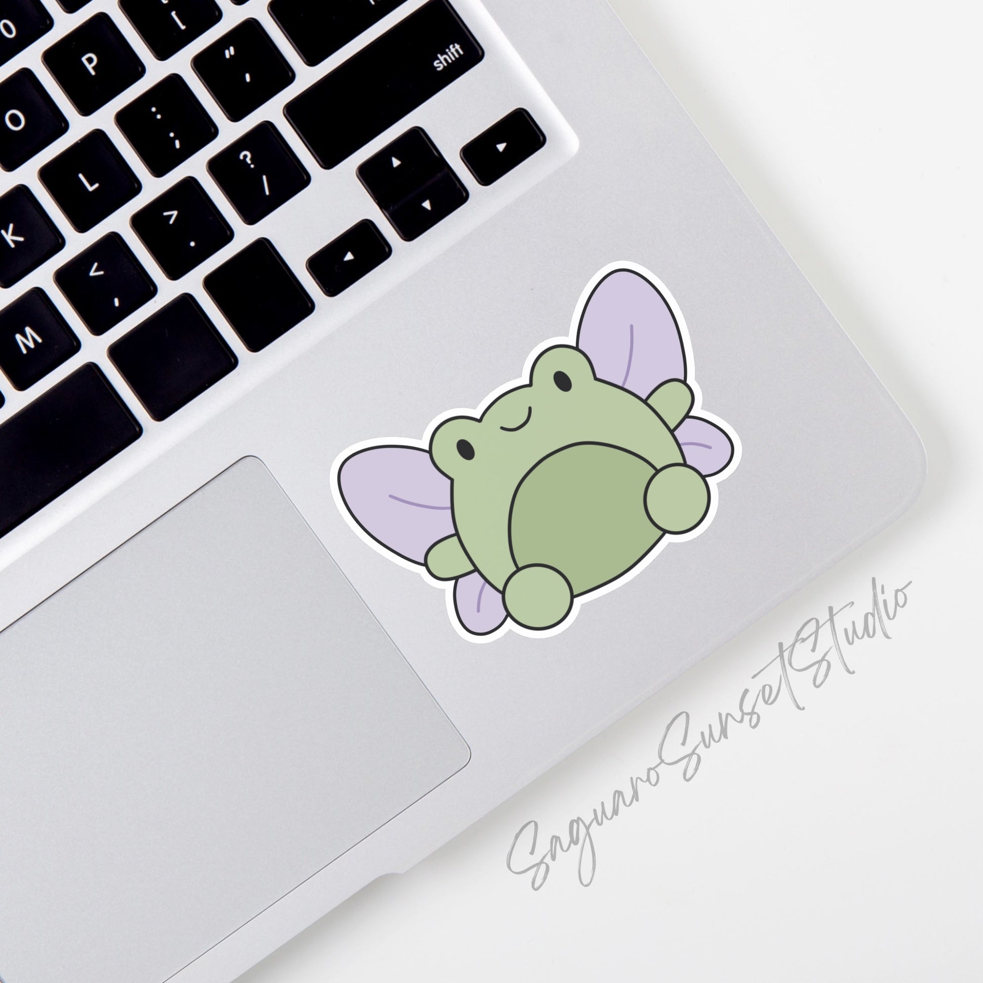 A vinyl sticker featuring a cute green frog with lilac colored fairy wings