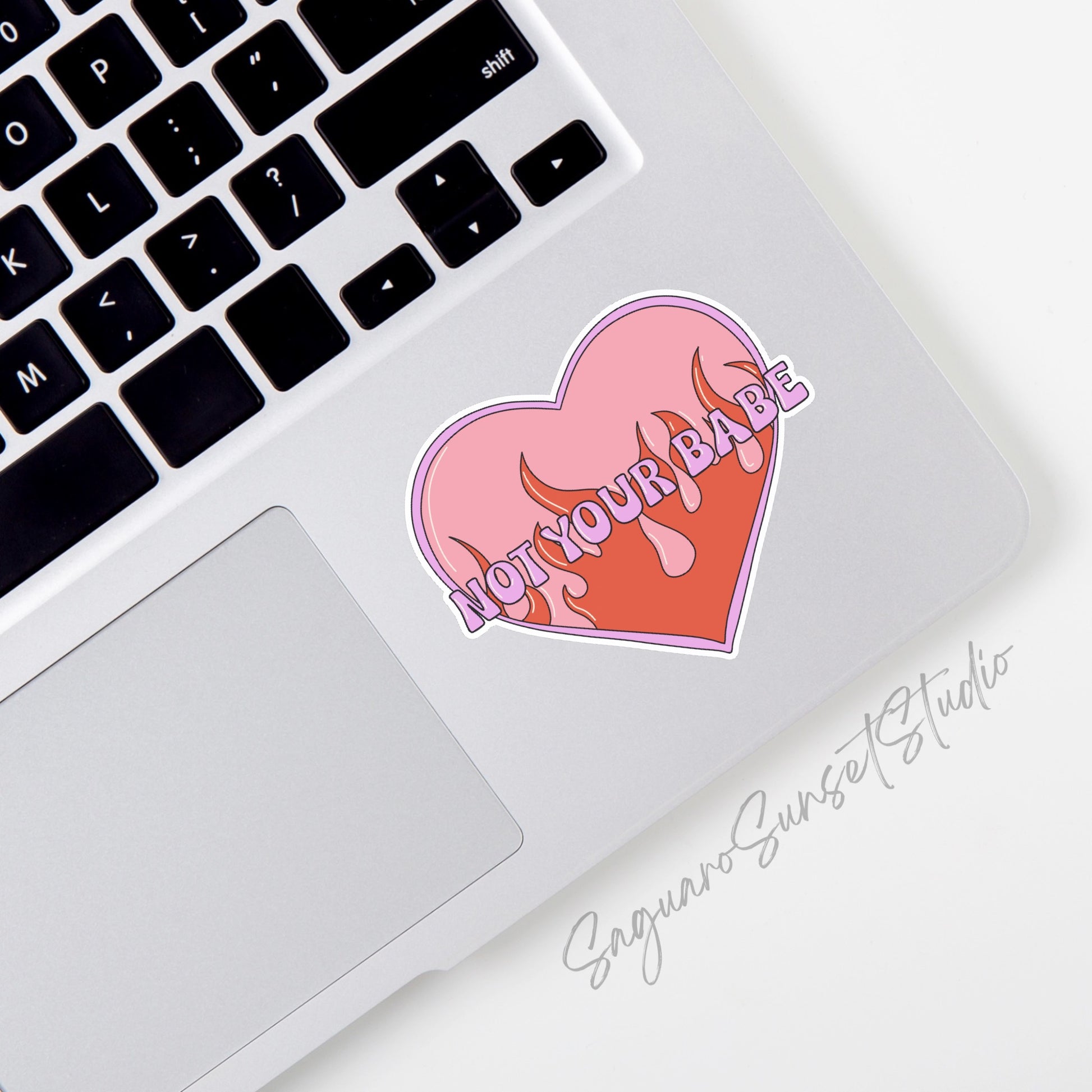 Sticker featuring a retro heart with flames and the phrase "Not Your Babe," designed to be cute, sassy, and evoke a Y2K aesthetic.