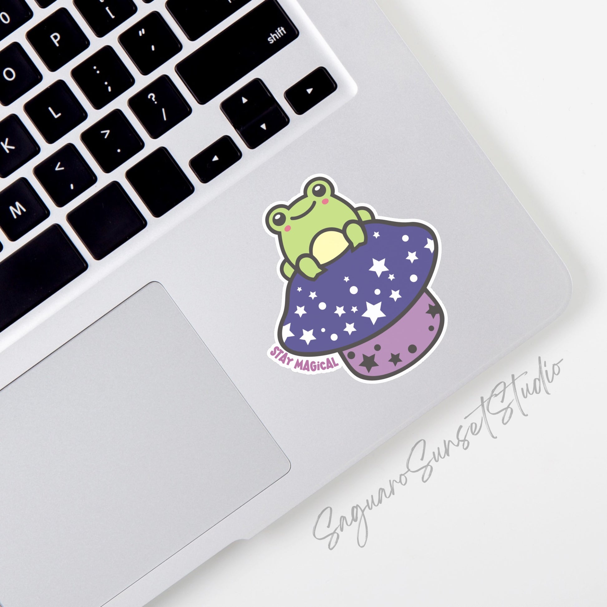 Sticker featuring a cute frog on a starry purple mushroom with the phrase "Stay Magical," designed to add enchantment to personal items.