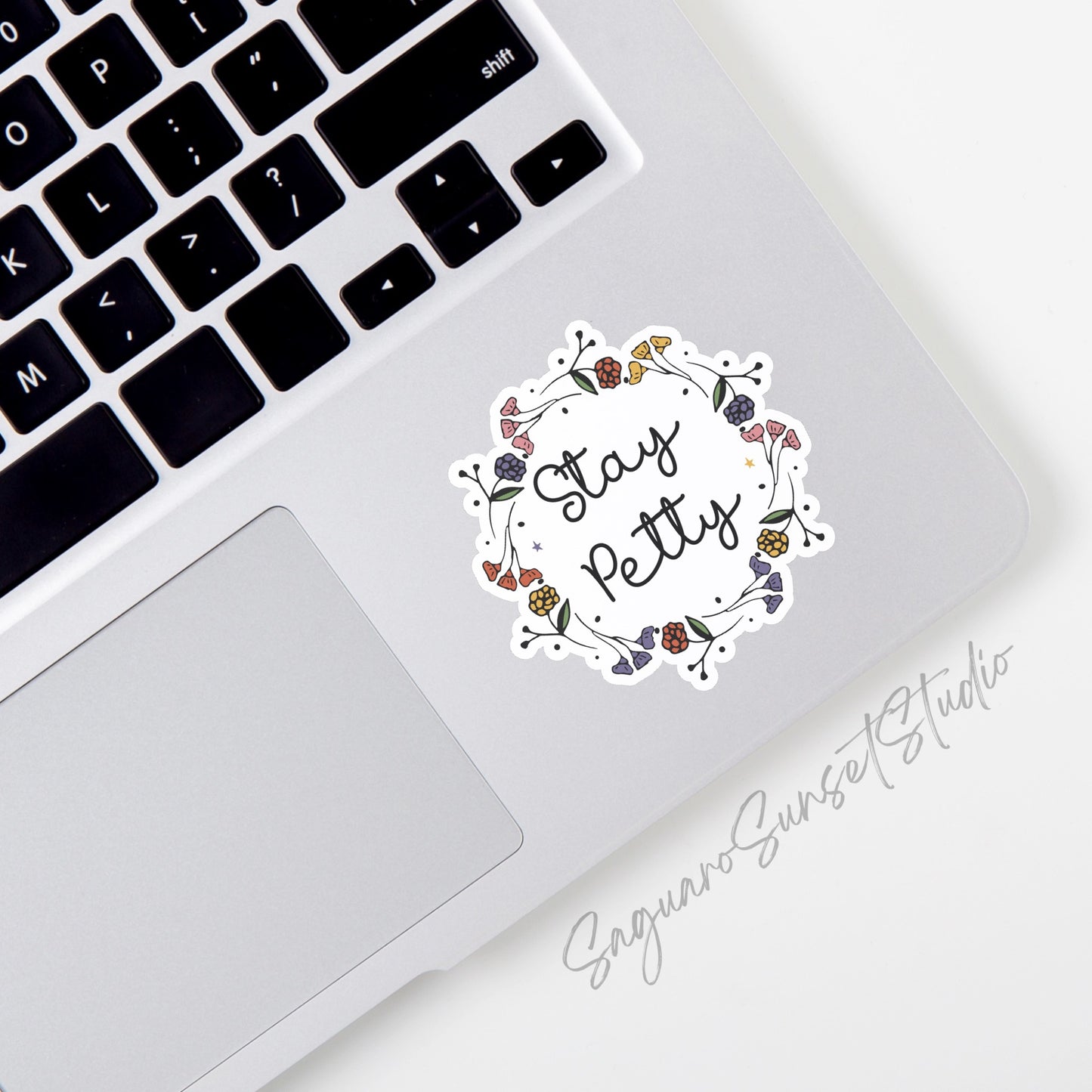 Sticker with the phrase "Stay Petty" surrounded by colorful floral accents, perfect for adding a touch of sass to your items.