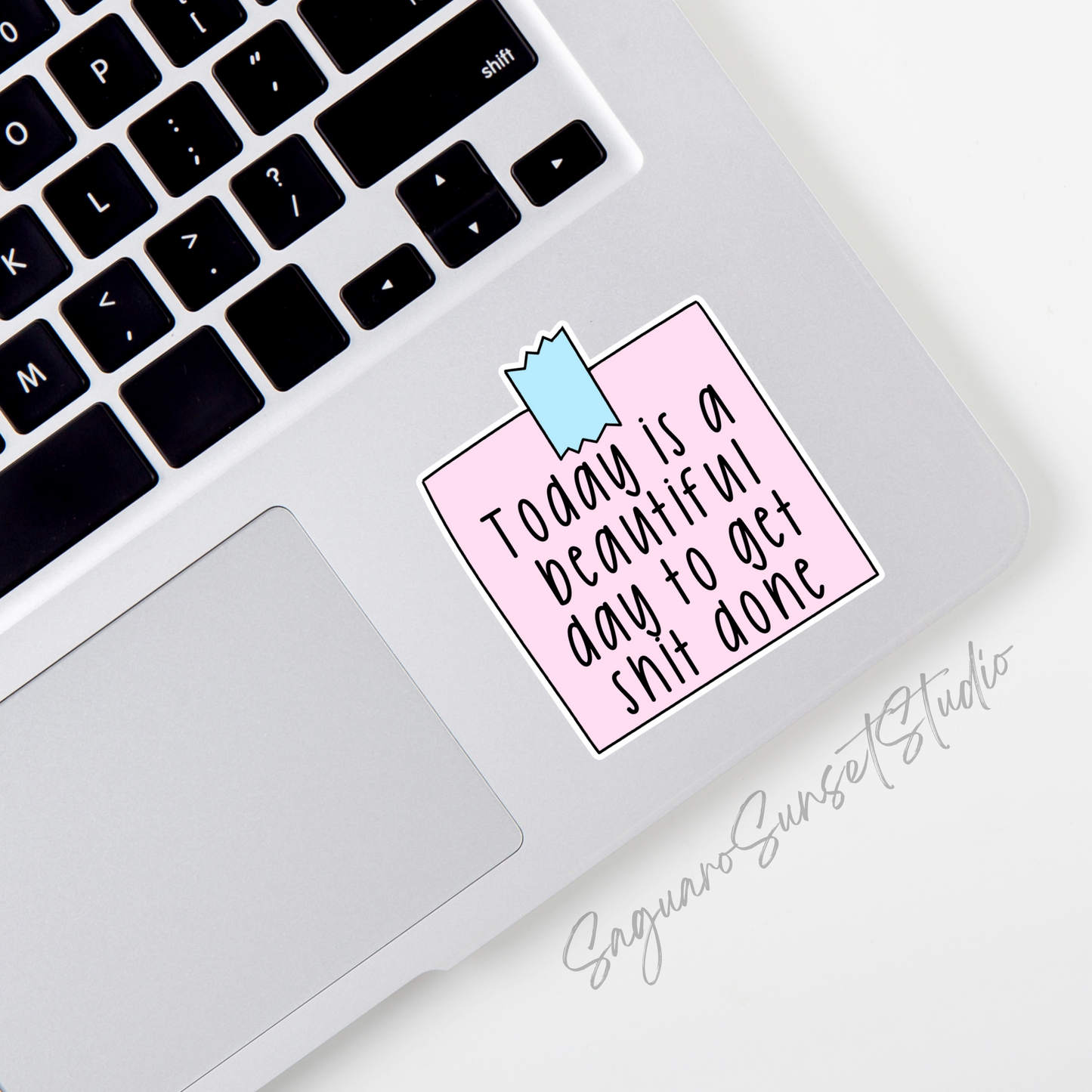Sticker with black handwritten text "Today is a beautiful day to get shit done" on a pastel pink background with a blue tape design at the top.