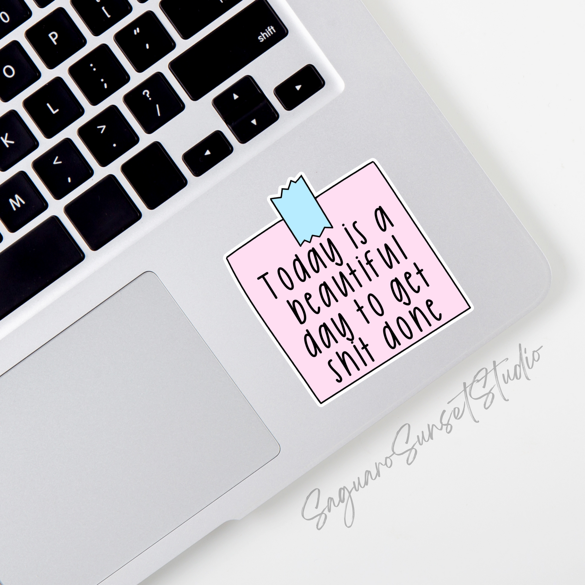 Sticker with black handwritten text "Today is a beautiful day to get shit done" on a pastel pink background with a blue tape design at the top.