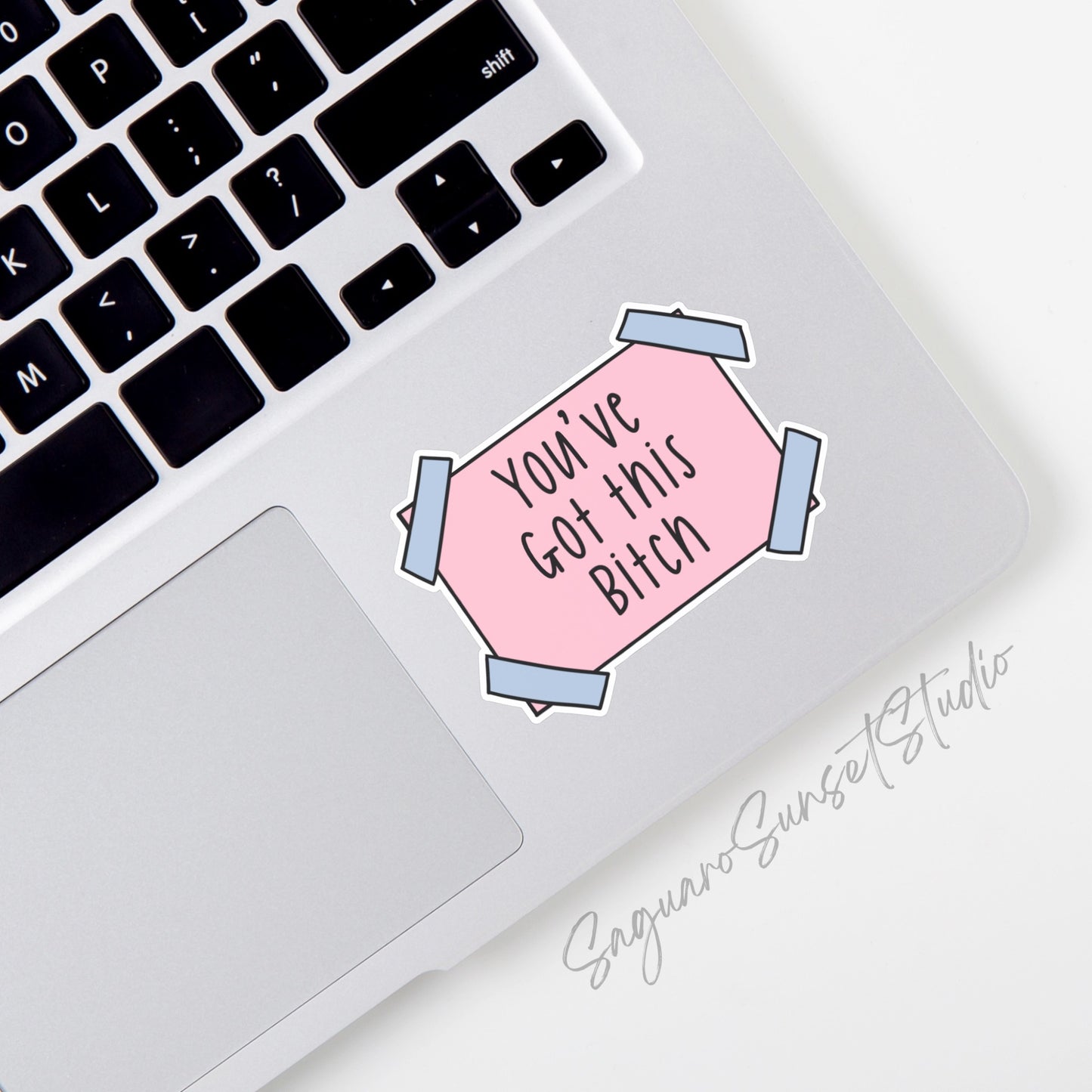 A sticker with the phrase "You've Got this Bitch" written in black text on a pink rectangular background. The sticker has blue tape corners.