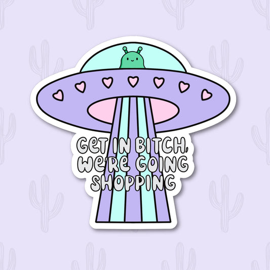 A vinyl sticker featuring a cute alien in a pastel-colored UFO with the phrase "Get In Bitch, We're Going Shopping" written below