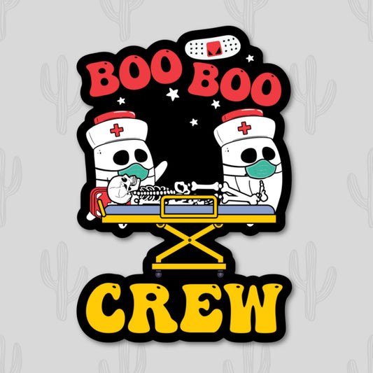 A sticker featuring the phrase "Boo Boo Crew" in bold red and yellow text. The design includes cartoon ghost nurses in masks tending to a skeleton patient on a stretcher, set against a starry black background.