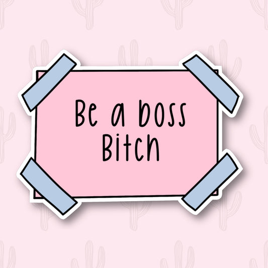 A pink sticker with blue taped corners featuring the phrase 'be a boss bitch'.