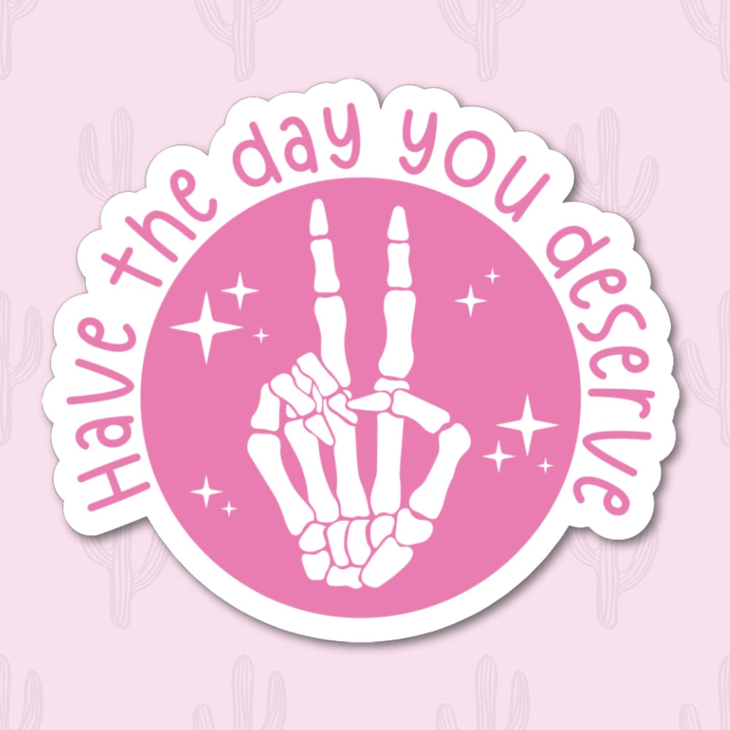 A vinyl sticker featuring a skeleton hand giving a peace sign with the phrase "Have the Day You Deserve" written around it