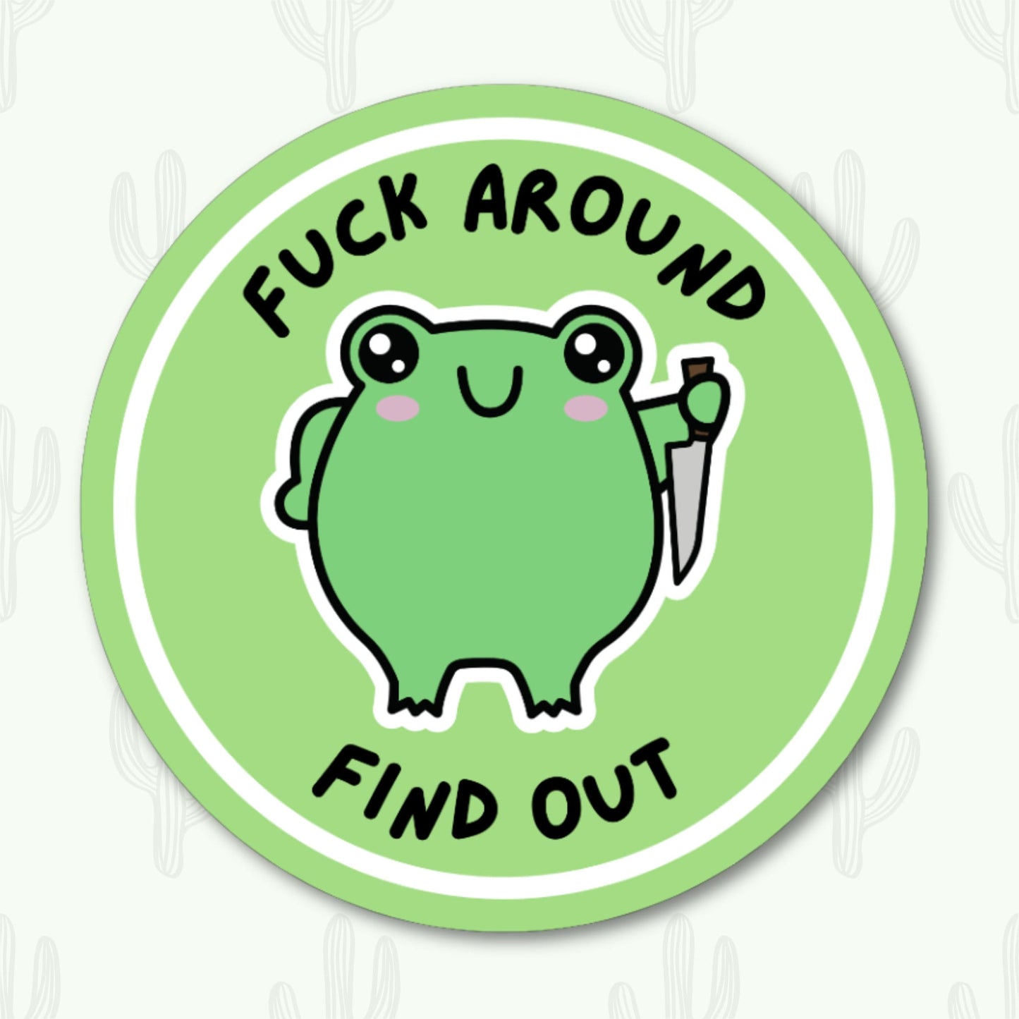 A round vinyl sticker featuring a cute green frog holding a knife, with the phrase "Fuck Around Find Out" in bold black text