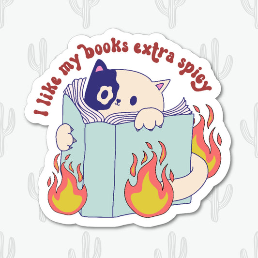 Sticker with the text "I Like My Books Extra Spicy" featuring a cute cat peeking over a book with playful flames. 