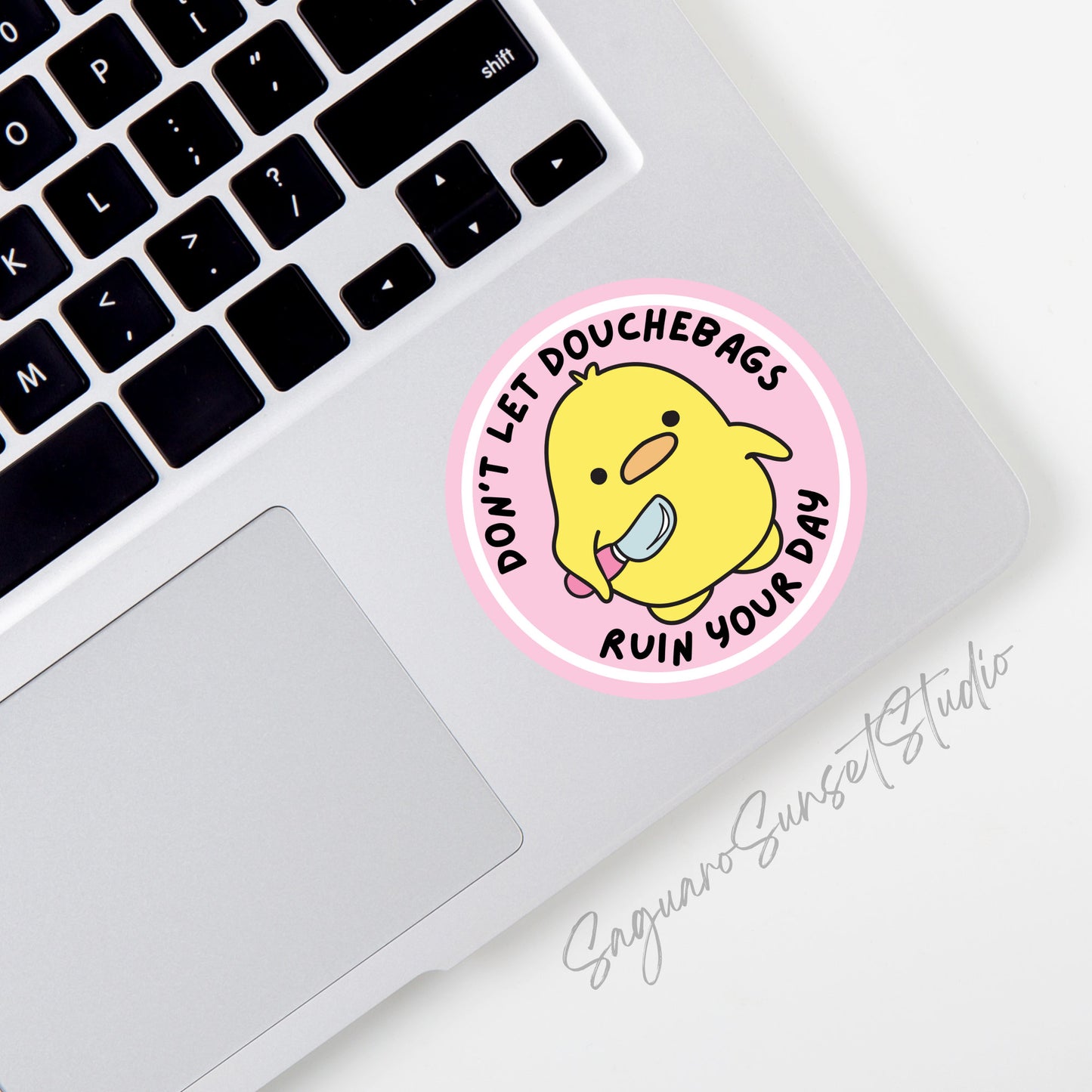 A round sticker featuring an adorable yellow duck holding a small knife, with the phrase "Don't Let Douchebags Ruin Your Day" written in black text around the duck.