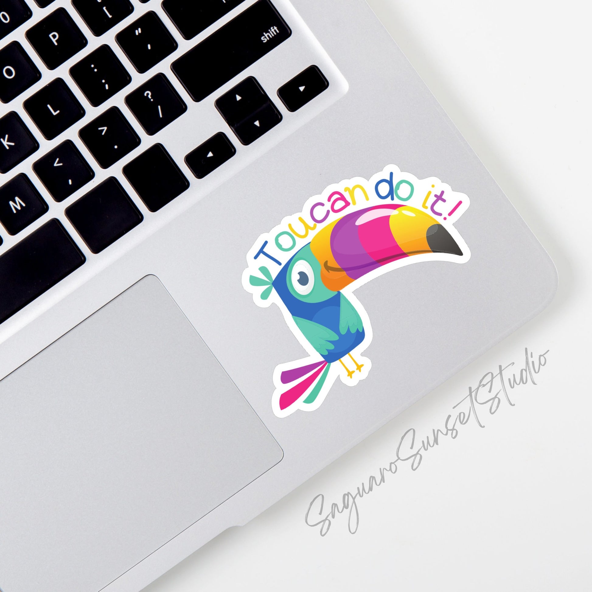 A cartoon toucan sticker with the text "toucan do it!" in bold letters, encouraging determination and positivity. The sticker is on the corner of a laptop.